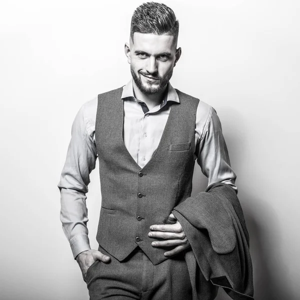 Handsome young elegant man in grey classic vest pose against studio background. — Stock Photo, Image