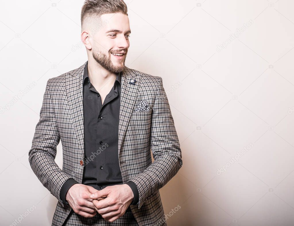 Handsome young elegant man in grey jacket pose against studio background.