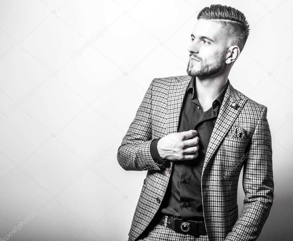 Handsome young elegant man in grey jacket pose against studio background. Black-white portrait.