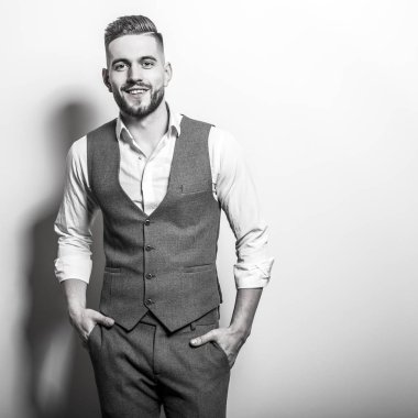 Zarif yakışıklı genç gri klasik yelek içinde poz studio arka planı.