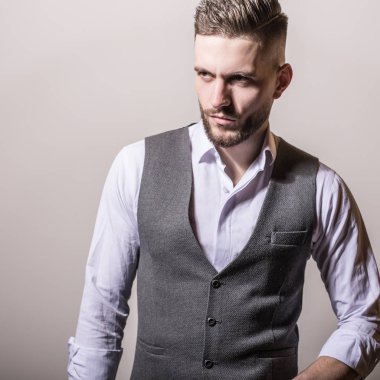 Zarif yakışıklı genç gri klasik yelek içinde poz studio arka planı.