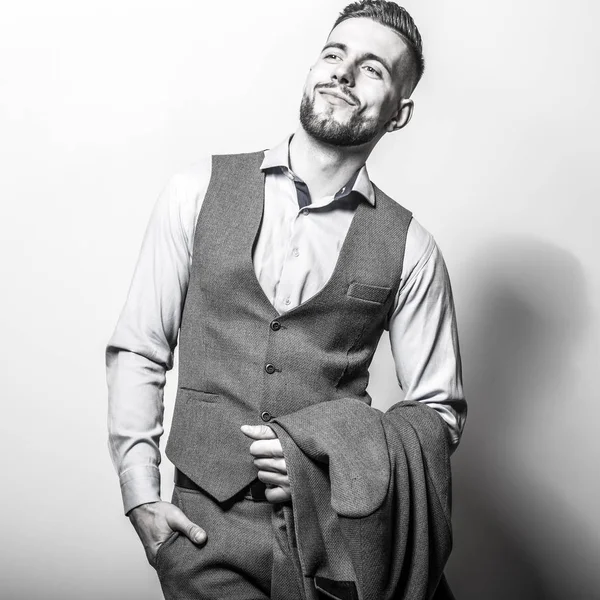 Bello giovane uomo elegante in grigio classico gilet posa contro lo sfondo dello studio . — Foto Stock