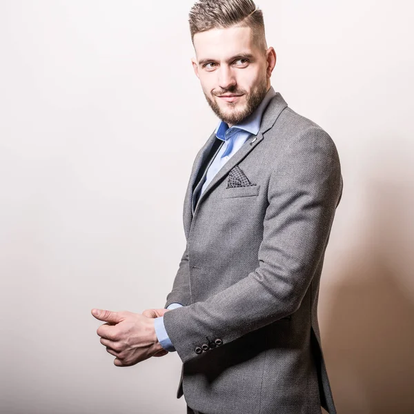 Guapo joven elegante hombre en gris chaqueta pose sobre fondo de estudio . —  Fotos de Stock