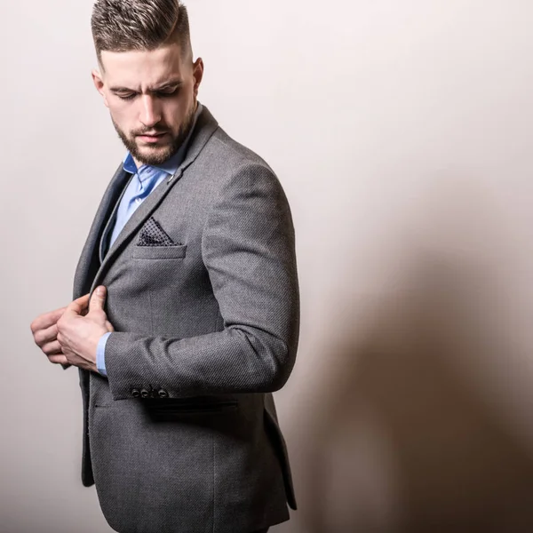 Guapo joven elegante hombre en gris chaqueta pose sobre fondo de estudio . —  Fotos de Stock