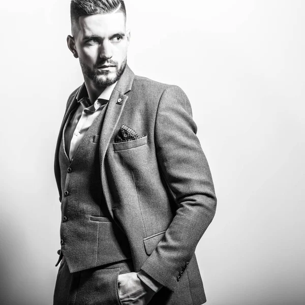 Handsome young elegant man in grey jacket pose against studio background. Black-white portrait. — Stock Photo, Image