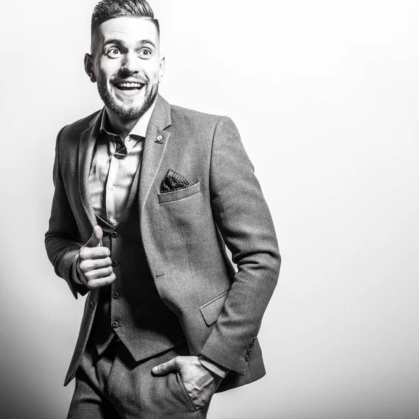 Handsome young elegant man in grey jacket pose against studio background. Black-white portrait. — Stock Photo, Image