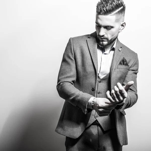 Beau jeune homme élégant en veste grise pose sur fond de studio. Portrait noir-blanc . — Photo