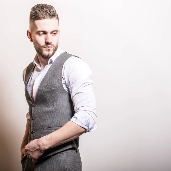 Hombre elegante joven guapo en chaleco clásico gris posan contra fondo de estudio . — Foto de Stock