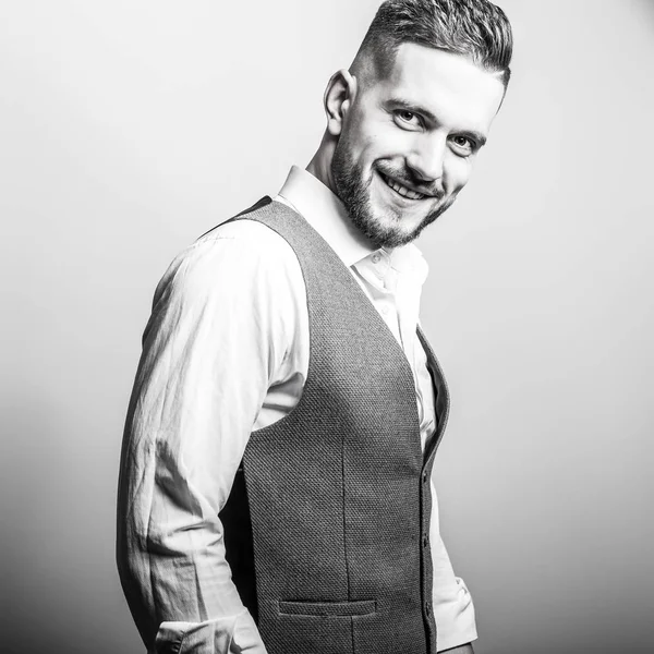 Handsome young elegant man in grey classic vest pose against studio background. — Stock Photo, Image