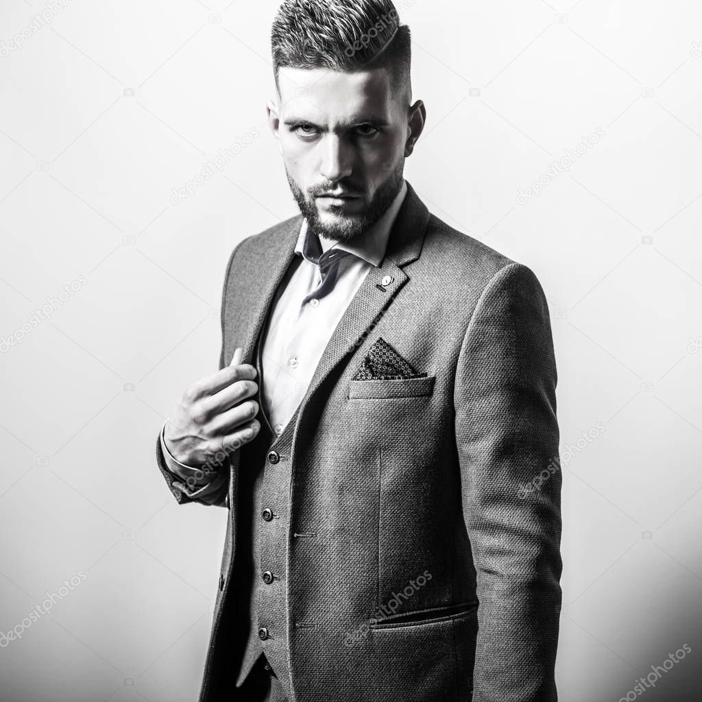 Handsome young elegant man in grey jacket pose against studio background. Black-white portrait.