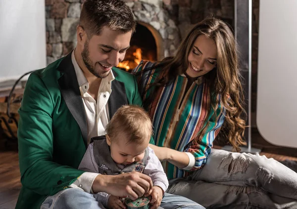 Young happy family together in interior of house with fireplace. — Stock Photo, Image