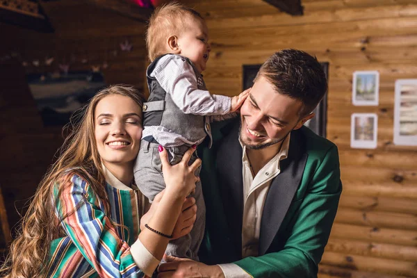 Young happy family together in interior of wooden house. — Stock Photo, Image