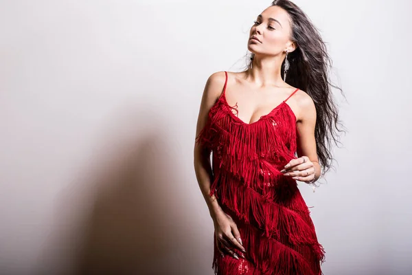 Jonge sensuele vrouw in rode jurk poseren in studio. — Stockfoto