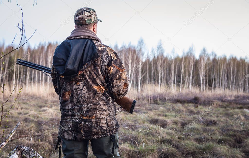 Hunter with a gun tracks down ducks on the river.