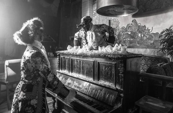 Actors in Steam punk masks and antique costumes indoor. Black-white photo.