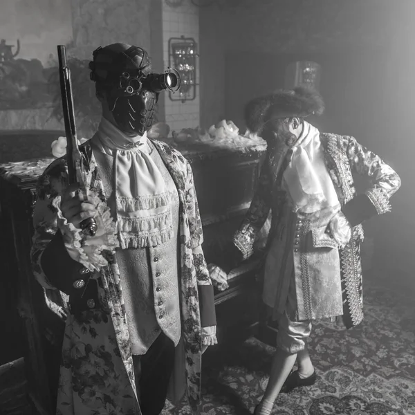 Actors in Steam punk masks and antique costumes indoor. Black-white photo.