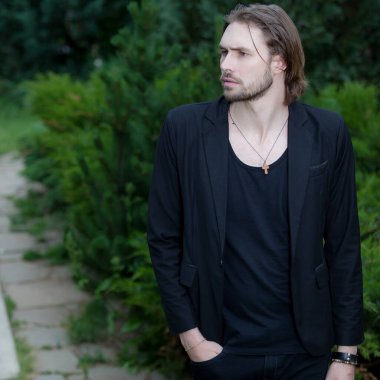 Dışarıda poz veren zarif yakışıklı genç adam..