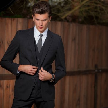 Dışarıda poz veren zarif yakışıklı genç adam..