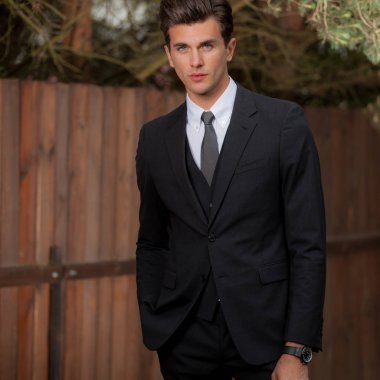 Dışarıda poz veren zarif yakışıklı genç adam..