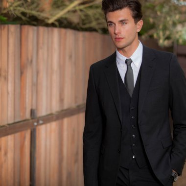 Dışarıda poz veren zarif yakışıklı genç adam..