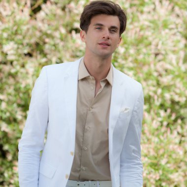 Dışarıda poz veren zarif yakışıklı genç adam..