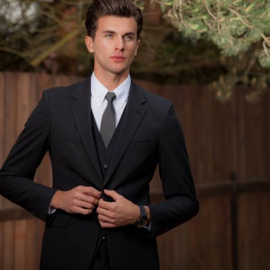 Dışarıda poz veren zarif yakışıklı genç adam..