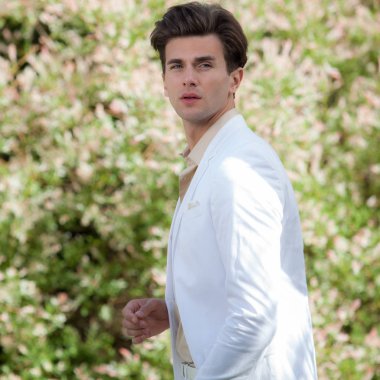 Dışarıda poz veren zarif yakışıklı genç adam..