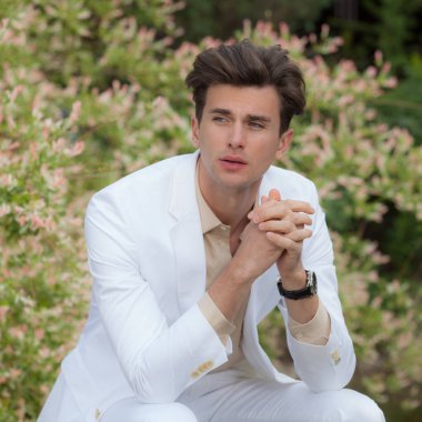 Dışarıda poz veren zarif yakışıklı genç adam..