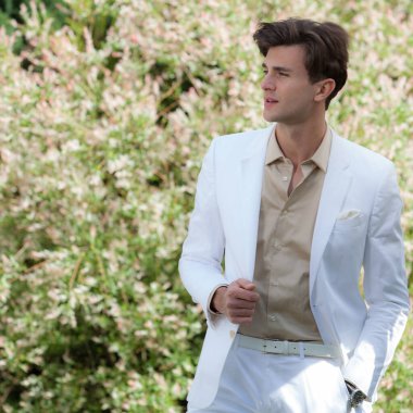 Dışarıda poz veren zarif yakışıklı genç adam..