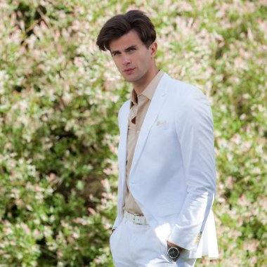 Dışarıda poz veren zarif yakışıklı genç adam..