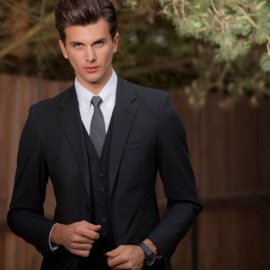 Dışarıda poz veren zarif yakışıklı genç adam..