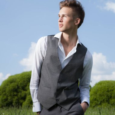 Dışarıda poz veren zarif yakışıklı genç adam..