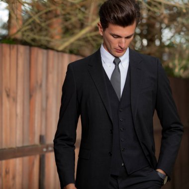 Dışarıda poz veren zarif yakışıklı genç adam..