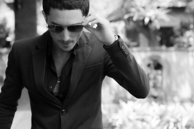 Dışarıda poz veren zarif yakışıklı genç adam..