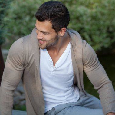 Dışarıda poz veren zarif yakışıklı genç adam..