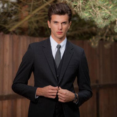 Dışarıda poz veren zarif yakışıklı genç adam..