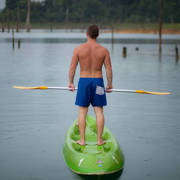 A fiatal sportember kajakozik a tóban.. — Stock Fotó