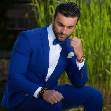 Dışarıda poz veren zarif yakışıklı genç adam..