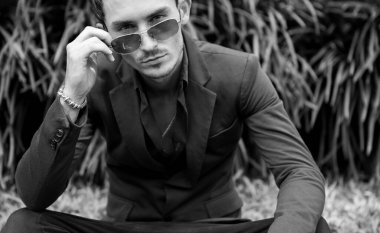 Dışarıda poz veren zarif yakışıklı genç adam..