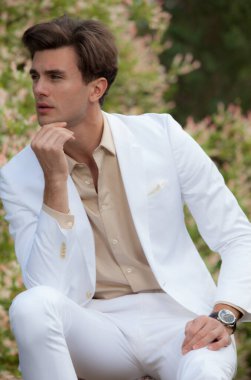 Dışarıda poz veren zarif yakışıklı genç adam..