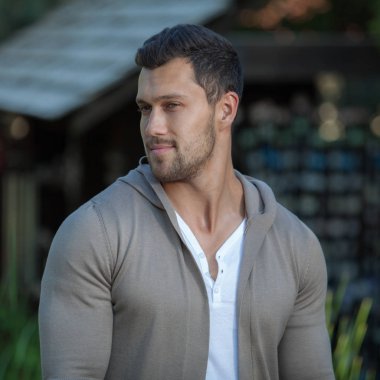 Dışarıda poz veren zarif yakışıklı genç adam..