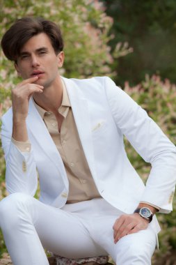 Dışarıda poz veren zarif yakışıklı genç adam..