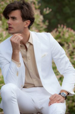 Dışarıda poz veren zarif yakışıklı genç adam..