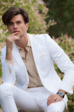 Dışarıda poz veren zarif yakışıklı genç adam..