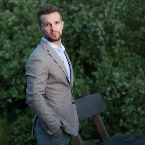 Dışarıda poz veren zarif yakışıklı genç adam..