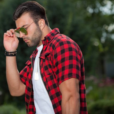 Dışarıda poz veren zarif yakışıklı genç adam..