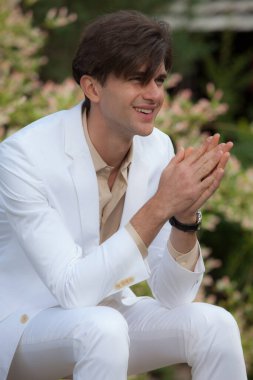 Dışarıda poz veren zarif yakışıklı genç adam..