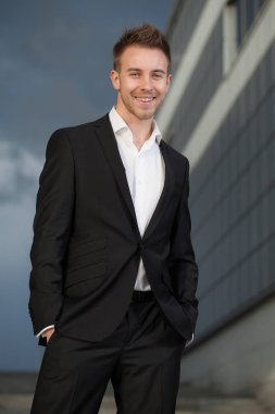 Dışarıda poz veren zarif yakışıklı genç adam..