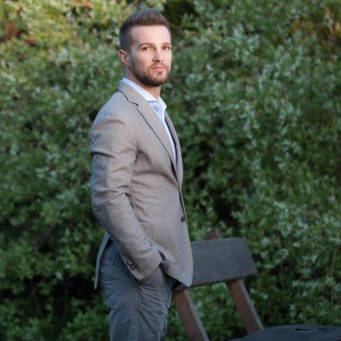 Dışarıda poz veren zarif yakışıklı genç adam..