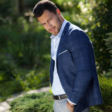 Dışarıda poz veren zarif yakışıklı genç adam..